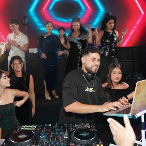 תקליטן לחתונה די ג'יי עומרי חיים בעמדה בתוך הרחבה מוקף באנשים